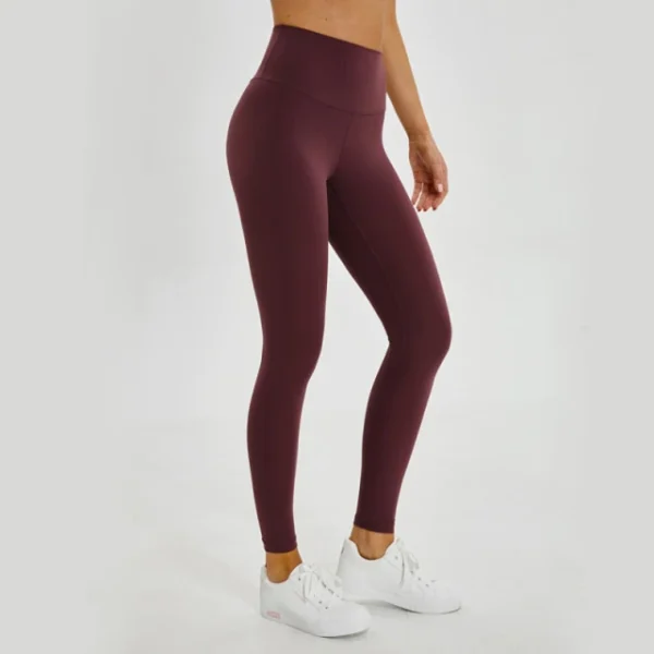 A woman is wearing maroon leggings and white shoes.