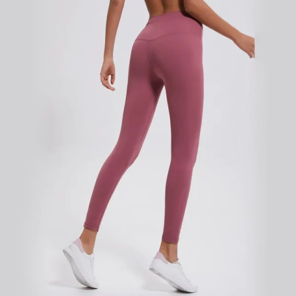 A woman is wearing pink leggings and white sneakers.