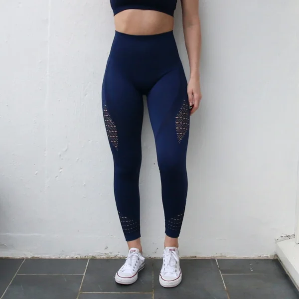 A woman standing in front of a wall wearing blue leggings.