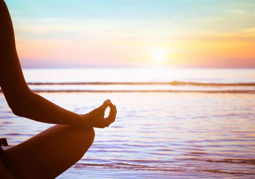 A person sitting in the lotus position on the beach